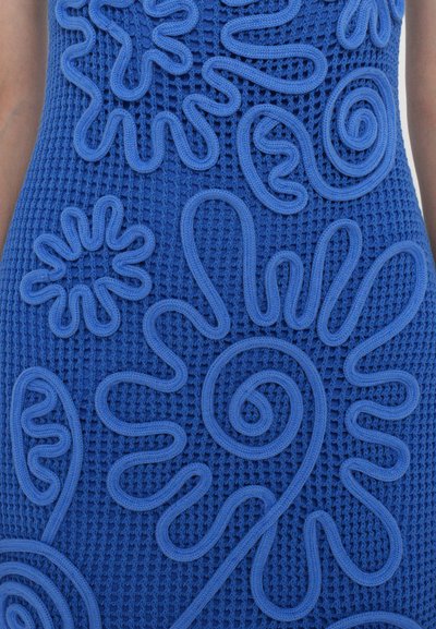 Vestido azul texturizado con bordados en relieve y en forma de ondas en diversas formas florales y espirales, creando un patrón dinámico a través de la tela.