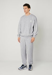 Set di felpa e pantaloni grigio heather realizzato in tessuto morbido, con una vestibilità comoda, maniche a costine e una piccola etichetta con logo sul petto.