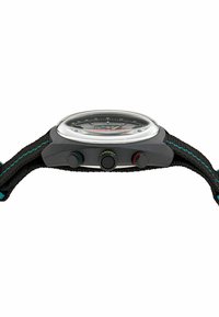 Zegarek z czarnym plecionym paskiem, wielokolorowymi akcentami, okrągłą przezroczystą szklaną kopułą i trzema bocznymi przyciskami. Okrągła tarcza z cyfrowymi znacznikami.