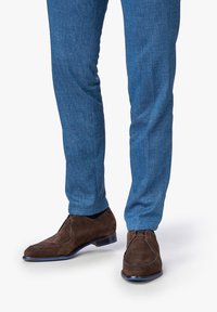 Scarpe in suede marrone con un design elegante e accenti blu, abbinate a pantaloni blu con texture, che mostrano uno stile slim fit.