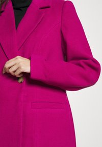 Fuschia tailored coat with a textured finish, featuring a single button closure, notch lapels, and a chest pocket.