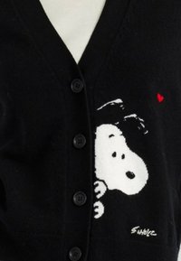 Cardigan nero con scollo a V, con un'illustrazione di Snoopy bianco e un piccolo cuore rosso. Cinque bottoni neri lungo la parte frontale.