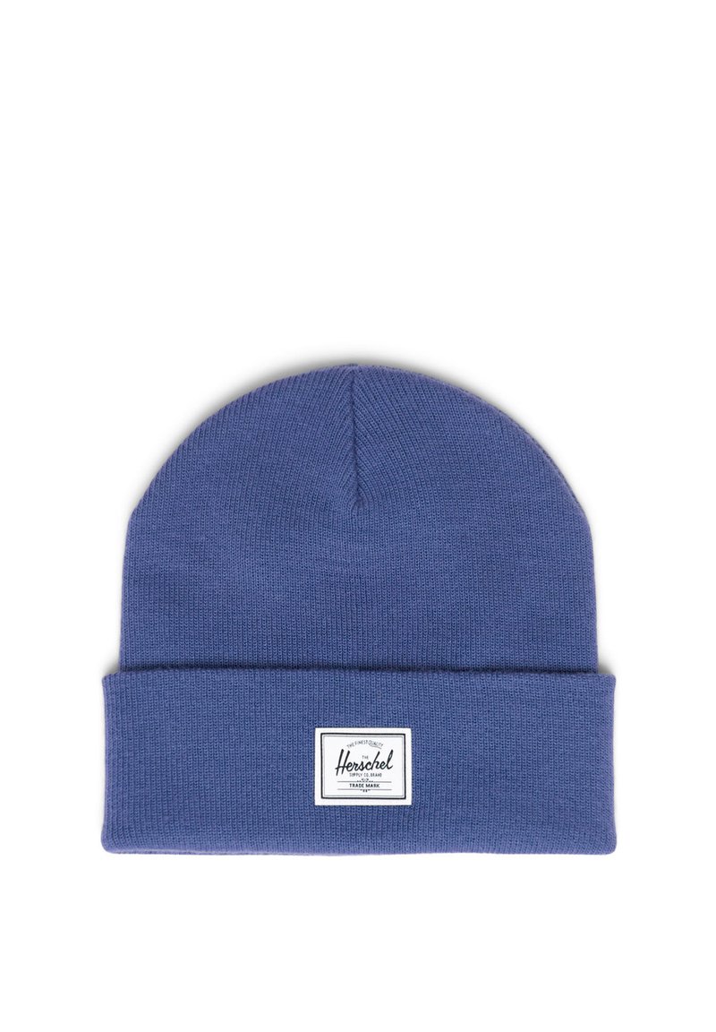 Modrá pletená čepice s ohrnutým lemem, s obdélníkovou bílou štítkem s černým logem. Měkká textura, bezšvy design a zakulacený vrchol.