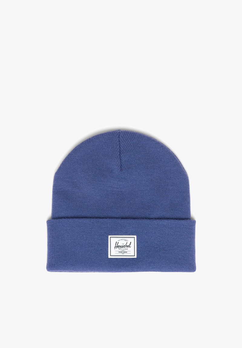 Modrá pletená čepice s ohrnutým lemem, s obdélníkovou bílou štítkem s černým logem. Měkká textura, bezšvy design a zakulacený vrchol.