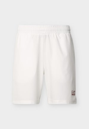 Valged spordipüksid elastse taljega ja väike punane EA7 Emporio Armani logo parema sääre alumisel osal.