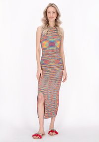 Abito maxi lavorato a maglia con un motivo a righe multicolori, caratterizzato da un collo rotondo e uno spacco laterale. Abbinato a sandali decorati con elementi decorativi.