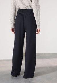 Tengerészkék, széles szárú nadrág gumis derékrésszel és egy hátsó zsebbel, puha, rugalmas anyagból készült.