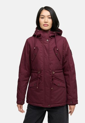 Giacca isolante bordeaux con un ampio cappuccio, vita regolabile con coulisse e quattro tasche a pattina. Tessuto morbido con finitura texturizzata e dettagli in bottone.
