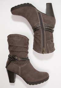 Botines de ante gris con diseño holgado, con una cremallera lateral, correas decorativas, detalles dorados y un tacón grueso negro.