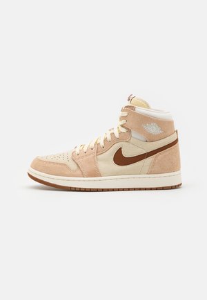 Wysokie buty Air Jordan w odcieniach beżu, kremu i brązu z panelami z zamszu i siateczki, logo Nike Swoosh oraz skrzydlate logo Air Jordan przy kostce.