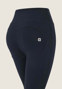Navyblaue, hoch taillierte Leggings aus dehnbarem Material mit einem gebogenen Nahtdesign und kleinem Logo auf der hinteren Tasche.