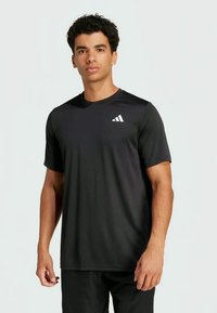 Svart treningst-skjorte laget av et fukttransporterende materiale, med rund hals og en hvit logo på venstre bryst.