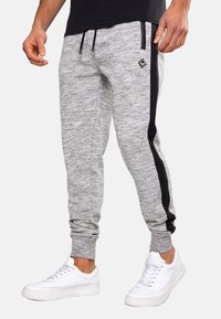 Grey jogger pants made of a textured fabric with a black side stripe; features an adjustable drawstring waistband and tapered fit.