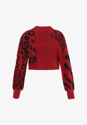 Punainen lyhyt villatakki, jossa on pörröinen rakenne; mustat leopardin- ja eläinkuosilla varustetut yksityiskohdat hihoissa; pyöreä pääntie; pitkät hihat.