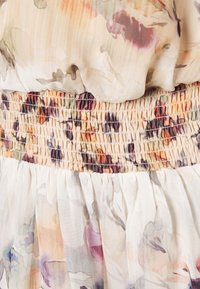 Vestido con estampado floral que presenta una blusa ligera y transparente con cinturilla elástica fruncida y una falda fluida en tonos pasteles.