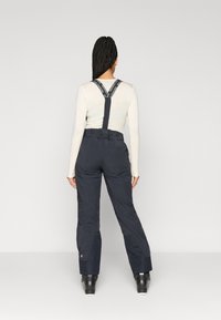 Marineblauwe skioveralls van stevige stof, verstelbare banden met branding, taps toelopende benen en een met riem verstelbare taille voor een veilige pasvorm.