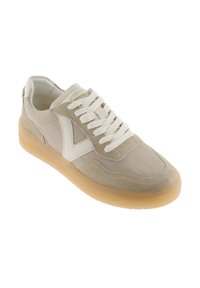 Sneaker beige e marrone chiaro con lacci bianchi, pannelli in camoscio e pelle, suola semitrasparente color gomma, inclinata per mostrare il lato esterno.