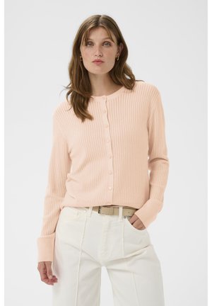 Hellrosa gerippte Strickjacke mit Knopfleiste, langen Ärmeln und rundem Ausschnitt, kombiniert mit weißen, hoch taillierten Hosen.