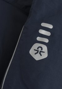 Navyfarbener Stoff mit glatter Textur zeigt ein silbernes Symbol, das Zugänglichkeit darstellt, und drei horizontale Linien darüber.