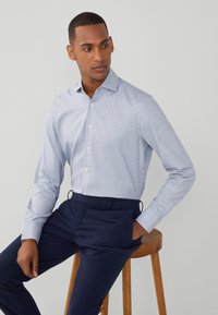 Camicia fitted azzurro chiaro con un sottile motivo a quadri, colletto button-down, maniche lunghe, abbinata a pantaloni blu navy.