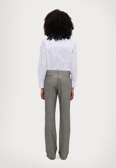 White long-sleeve shirt with bow details on sleeves, paired with gray wool blend trousers, straight-cut and textured fabric.