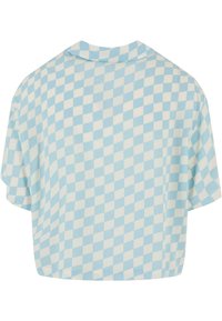 Kortermet, crop-top i lyseblå og kremfarget rutete mønster. Myk stoff med avslappet passform og ribbet krage.