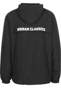 Black hooded jacket featuring a contrasting white "URBAN CLASSICS" logo across the upper back. Lightweight fabric with elastic cuffs.