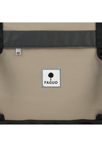 Beige tygväska med ett mörkt band, som har en Faguo-logotyp i svart och vitt. Texturerad yta med kontrasterande sömnadsdetaljer.