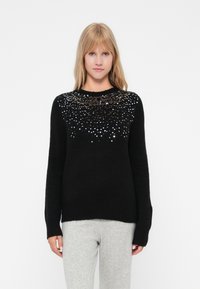 Maglione nero con scollo rotondo e maniche lunghe, caratterizzato da una sfumatura di paillettes metalliche nella parte superiore per i dettagli.