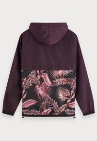 Lila huvmantel med långa ärmar som har en svart panel med rosa och mauve tropiska bladmönster på ryggen.