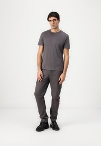 Graues kurzärmliges T-Shirt, kombiniert mit grauen Cargo-Hosen. Das Outfit hat eine lockere Passform, ein minimalistisches Design und schlichte schwarze Schuhe.