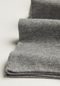 Grå stickade strumpor med en mjuk textur, som visar en vikbar design och ett subtilt räfflat mönster längs tyget.