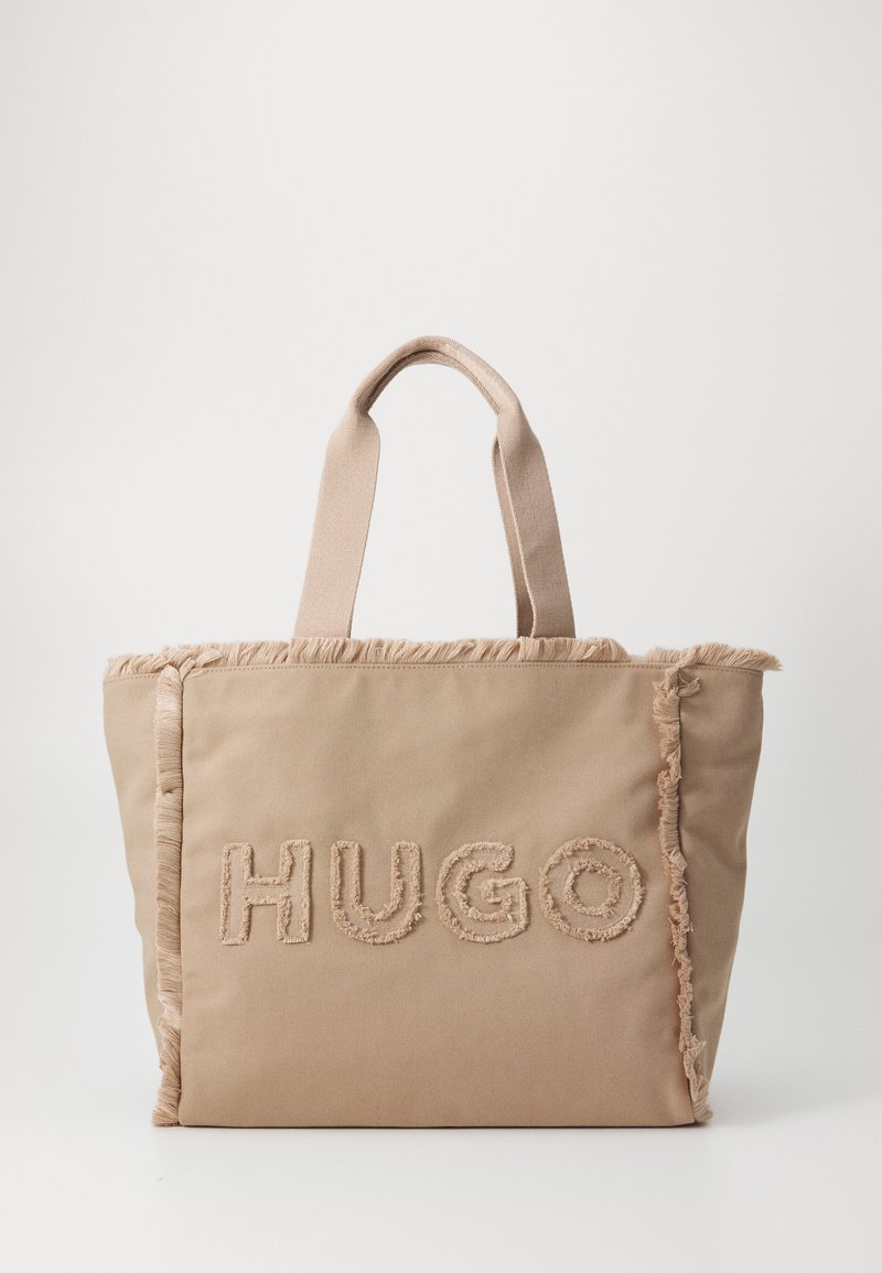 Bežna platnena torba s rastrganim rubovima i izvezenim "HUGO" logotipom. Ima dva platnena ručka i strukturirani oblik.