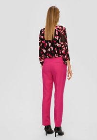 Roze op maat gemaakte broeken met een gladde textuur en achterzakken, gecombineerd met een zwart blouse met een roze en witte abstracte print.