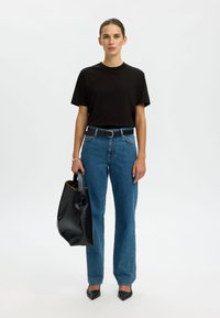 Črna bombažna majica, modre kavbojke z visokim pasom, črni usnjen pas, črna torba na rame in črni špičasti petki. Enostaven dizajn, raven kroj.