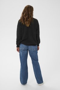 Black chunky knit sweater with long sleeves; paired with light blue wide-leg jeans; relaxed fit; plain design; no visible patterns or accents.