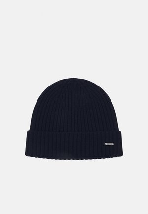 Beanie a coste verticale blu navy con risvolto e una piccola etichetta con logo. Tessuto morbido, tessuto spesso e parte superiore arrotondata.