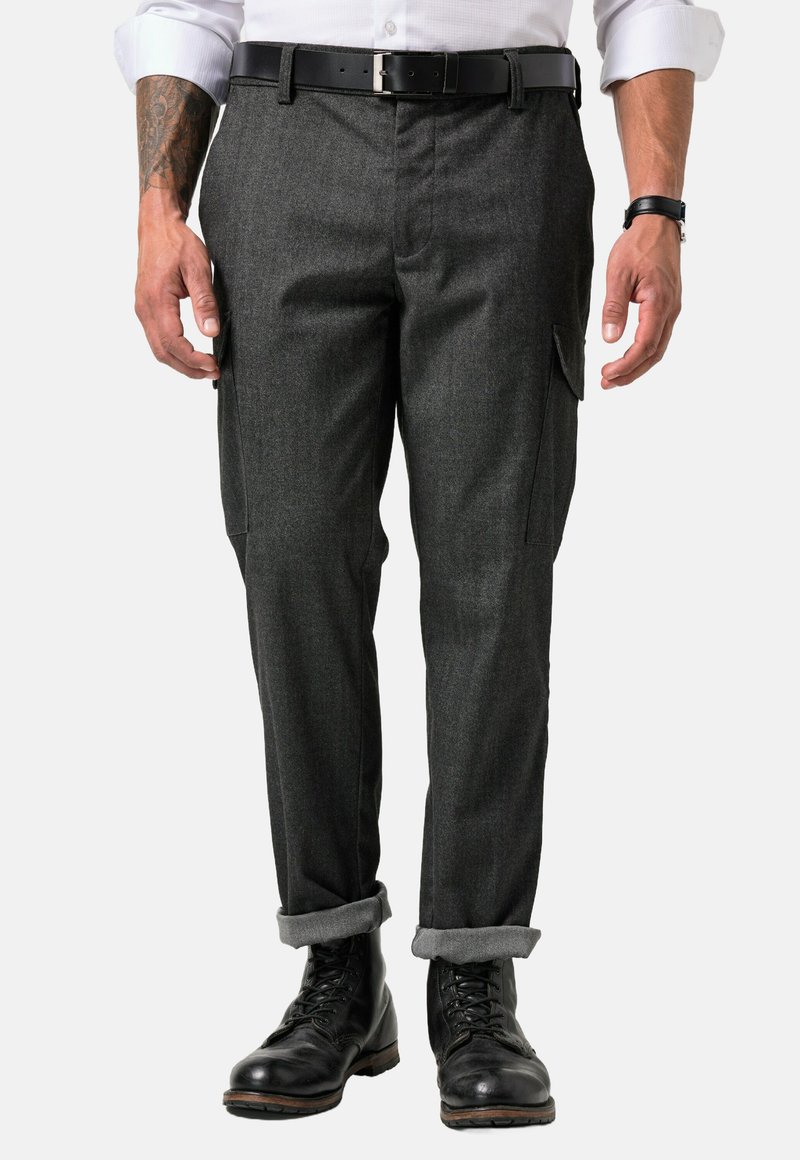 Dunkelgraue, maßgeschneiderte Hose mit strukturierter Oberfläche, seitlichen Taschen und umgeschlagenen Säumen, kombiniert mit schwarzen Lederstiefeln.