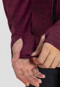Burgundy long-sleeve top with textured fabric, thumbholes at cuffs, and a fitted design. Smooth finish with slight variations in color.