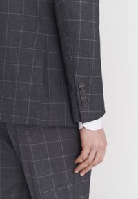 Szary marynarka w kratę o dopasowanym kroju, z gładkiego materiału, z czterema ciemnymi guzikami na mankietach, z białą koszulą widoczną pod spodem.