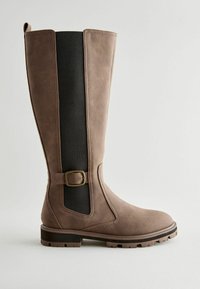 Tall brown leather boot with elastic black side panel, adjustable buckle accent, and sturdy treaded sole. Smooth texture and slightly tapered design.