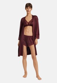 Burgunderfärgad underklädesset som inkluderar en bralette med spetsdetaljer, matchande shorts och en lång, spetsprydd kimono, tillverkad av mjukt material.