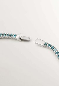 Pulsera de plata con un diseño trenzado, que presenta piedras preciosas azules colocadas en una fila a lo largo de su longitud y un detalle de cierre de extremos cuadrados.