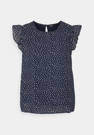 Marineblauwe mouwloze blouse met witte verspreide stippen en geruimde doorschijnende kapmouwtjes, ronde halslijn en sleutelgatknopsluiting aan de achterkant.