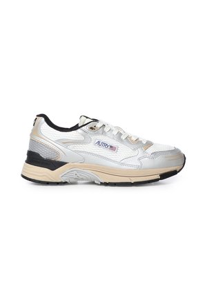 Zapatilla baja blanca y beige con suela negra y detalles, parte superior de malla y cuero, y logo "Autry" con una bandera estadounidense en el lateral.