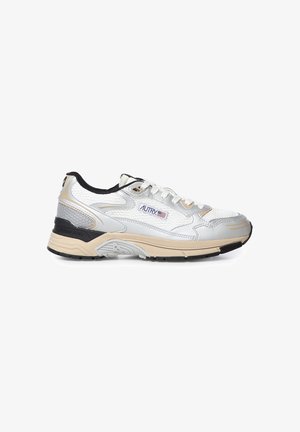 Zapatilla baja blanca y beige con suela negra y detalles, parte superior de malla y cuero, y logo "Autry" con una bandera estadounidense en el lateral.