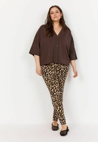 Brun, kortärmad knapp-up topp i kombination med beige leopardmönstrade leggings och svarta meshballerina, med en avslappnad passform och mjukt tyg.