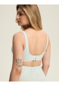 Jasnoniebieski, bezszwowy biustonosz z szerokimi ramiączkami i niskim plecami. Posiada regulowane zapięcie na haki oraz gładką, matową teksturę.