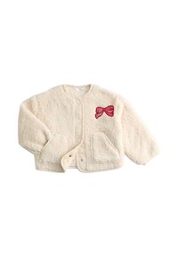 Giacca in pelliccia sintetica crema con scollatura arrotondata, bottoni a scatto, due tasche e un'applicazione a forma di fiocco rosso sul lato sinistro. Texture morbida, vestibilità rilassata.