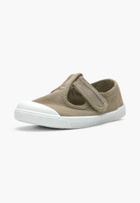 Une chaussure enfant en toile beige avec embout et semelle en caoutchouc blanc, avec une bride velcro réglable sur le dessus.
